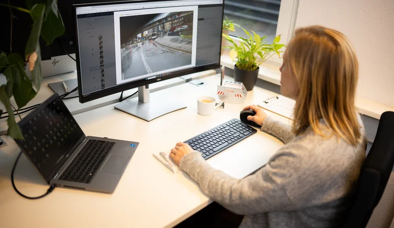 Frau sitzt bearbeitet Foto einer Straßenansicht am Computer