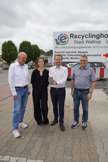 Vier Menschen vor einem Wertstoffhof