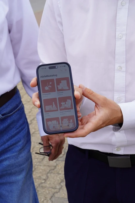 Hand hält Handy mit MAEX-App auf dem Display