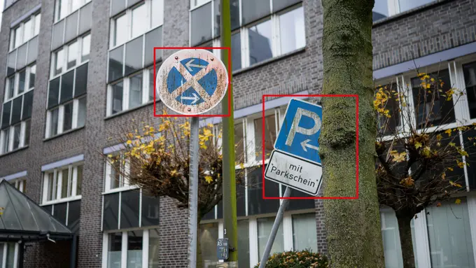 zwei verschmutzte Verkehrsschilder vor Bürogebäude